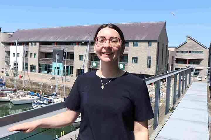 Heledd yn gwenu tu allan i'r swyddfa